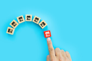 Fototapeta premium Franchise or franchising, Hand choose cube wooden toy block stack with franchises business store icon for growth and products services or branch expansion or bank loan.