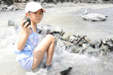 川の流れを石でせき止める女子小学生 (7歳)