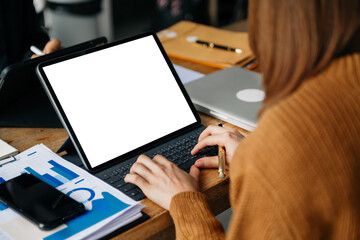 People using and looking at mockup laptop computer on wooden table together on office desk with...