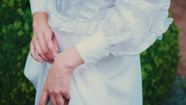 Fantasy red-haired dangerous woman medieval assassin queen with dagger in sheath on leg leather belt. White vintage old style dress. Girl princess warrior. Green summer nature trees. Hand hold knife