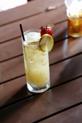 A view of a yellow colored cocktail in a highball glass.