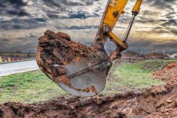 Close up of excavator bucket at construction site. The excavator is digging a trench for underground utilities. Construction equipment for earthworks. © Anoo