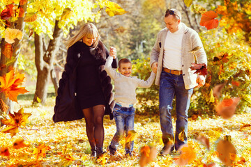 family walking in an autumn park with fallen fall leaves