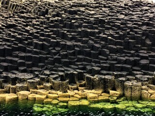 Pierres noires basaltiques en forme de cube baignant dans la mer