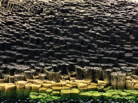 Pierres noires basaltiques en forme de cube baignant dans la mer