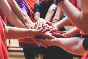 Team of kids children basketball players stacking hands in the court, sports team together holding hands getting ready for the game, playing indoor basketball, team talk with coach, close up of hands