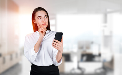 Pondering businesswoman standing touching chin holding smartphon