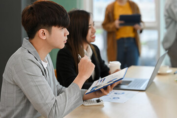 Young business men and women attend a meeting about business plans.