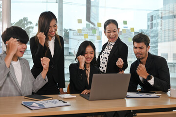 Middle-aged woman team leader and her team screaming with joy and celebrating by victory pose, Celebrating business success make great deal, great results, growth of sales concept.