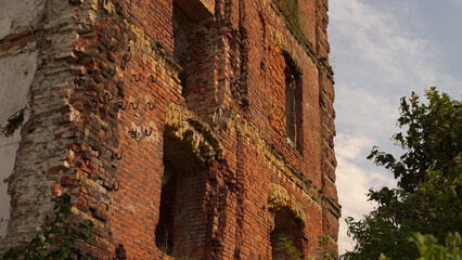 Old abandoned factory building made of red brick against a background of a beautiful blue sky. Half-destroyed Ukrainian plant. The walls of the old factory are ruined with age.