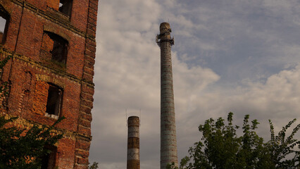 Two large abandoned industrial chimney pipes against a grey sky, close up. Old non-working smoke pipes of the industrial plant. Smokestack. Factory chimney pipes made of brick.