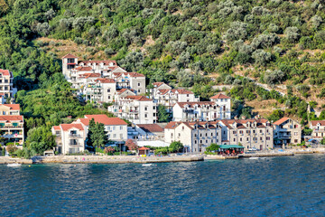 Fototapeta na wymiar Kotor, Montenegro - July 18, 2022: Shoreline buildings and piers outside of Kotor, Montenegro 