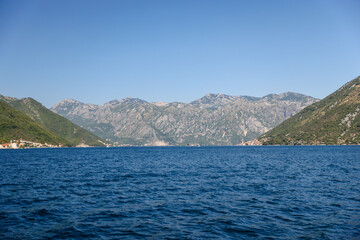 Fototapeta na wymiar Kotor, Montenegro - July 18, 2022: Shoreline buildings and cathedrals along the narrow fjord en route to Kotor, Montenegro 