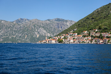 Fototapeta na wymiar Kotor, Montenegro - July 18, 2022: Shoreline buildings and cathedrals along the narrow fjord en route to Kotor, Montenegro 