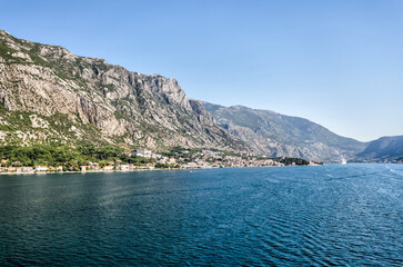 Fototapeta premium Kotor, Montenegro - July 18, 2022: Shoreline buildings and cathedrals along the narrow fjord en route to Kotor, Montenegro 