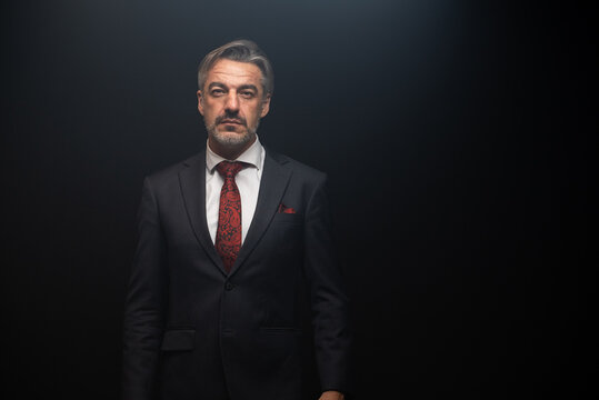 Portrait of senior Businessman standing in elegant black suit and red. isolated on black background.