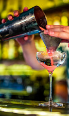 man hand bartender pouring pink sweet and sour refreshing cocktail in glass on the bar counter