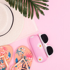 Summer beach background with hat and beach accessories on pastel pink background. Flat lay