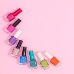 Creative composition of nail polish bottles in various colors on pastel pink background with copy space. Flat lay