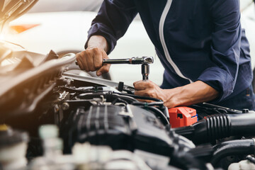 Automobile mechanic repairman hands repairing a car engine automotive workshop with a wrench, car service and maintenance,Repair service. - obrazy, fototapety, plakaty