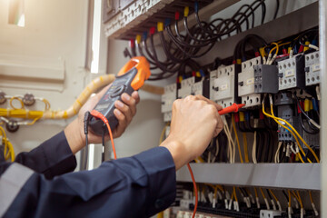 Electrical engineer using measuring equipment to checking electric current voltage at circuit...