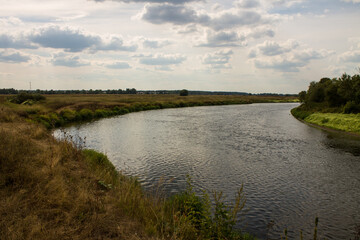 Beautiful landscape - the winding Klyazma river among the banks with green trees and a dramatic cloudy sky on a sunny day in August in the Moscow region