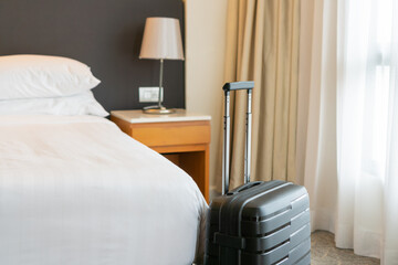 Black travel suitcase in bedroom or hotel room and window curtain background. Relaxing time on...