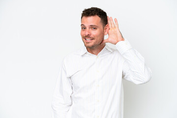 Young caucasian handsome man isolated on white background listening to something by putting hand on the ear