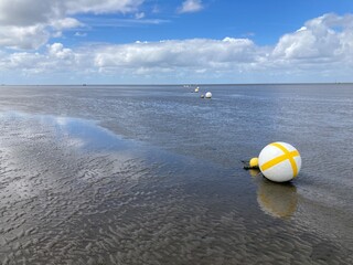 Obraz premium Markierungsbojen liegen bei Ebbe auf dem Meeresboden im Wattenmeer der Nordsee vor Cuxhaven 