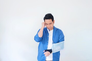 Patient with broken arm in sling, Asian man in casual blue shirt broken hand wearing an arm brace...