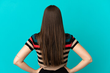 Teenager Brazilian girl over isolated blue background in back position