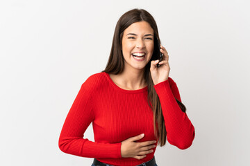 Teenager Brazilian girl using mobile phone over isolated white background smiling a lot