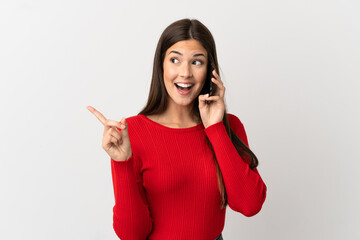 Teenager Brazilian girl using mobile phone over isolated white background intending to realizes the solution while lifting a finger up