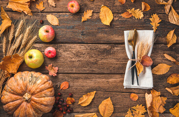 Autumn background with cutlery, pumpkin, apples and autumn foliage on a wooden table. The concept of Thanksgiving, Halloween. Top view, copy space