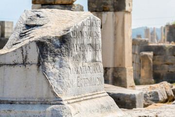 Ancient Greek inscription carved on the stone. defocused ruins at the background. Perge, or Perga...