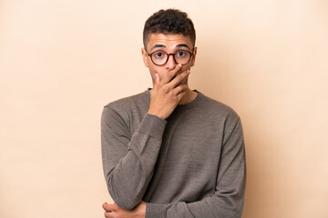 Young Brazilian man isolated on beige background surprised and shocked while looking right