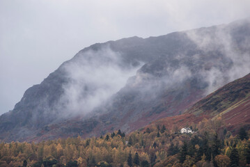 Stunning landscape image of Catbells viewed acros Derwentwater during Autumn in Lake District with mist rolling across the hills and woodland