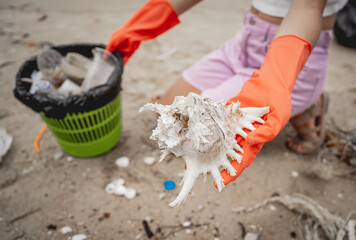 A female ecologist volunteer cleans the beach on the seashore from plastic and other waste
