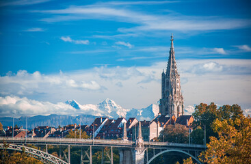Scenic view of tower of Munster cathedral in Bern, Switzerland. Snowcaped alpine peaks on...