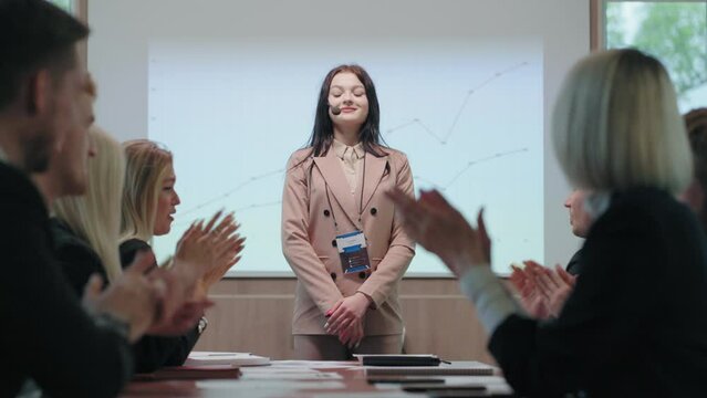 nervous woman is finishing her speaking in business meeting, colleagues are supporting her