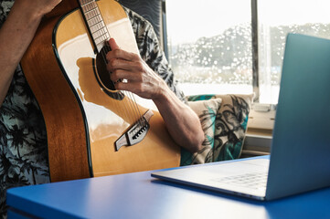 Man playing guitar and watching online tutorial