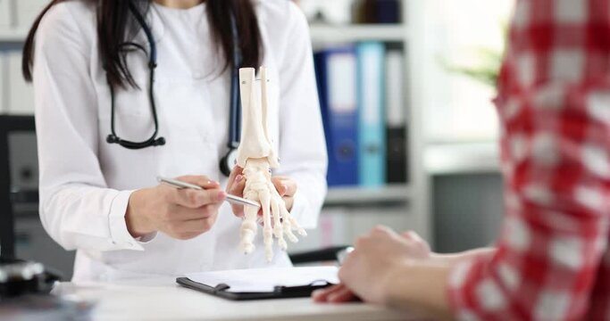 A woman orthopedist shows a model of a human foot