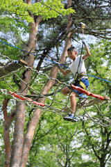 Naklejka na ściany i meble 木の上のアスレチックで遊ぶ男子中学生 (12歳)