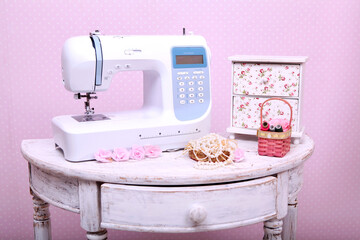 Composition from a sewing machine. Mannequin, flowers on a retro table and threads. Sewing supplies and composition with a sewing machine in the interior. With the letter M. for the fashion magazines