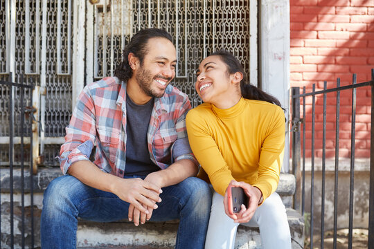 Smiling Mexican couple spending time on staircase on sunny day
