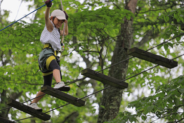 木の上のアスレチックで遊ぶ女子小学生 (7歳)