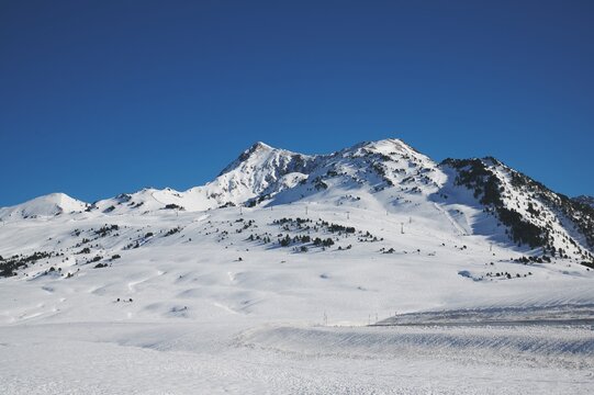 Mountain slope covered with snow under blue sky