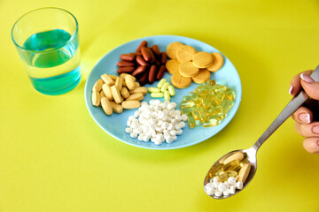 A handful of pills, capsules and multi-colored tablets on a plate next to cutlery. Taking medication. Pills instead of food. The concept of vitamins instead of food