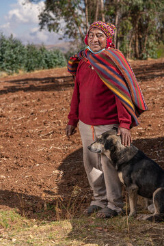 Smiling ethnic farmer with dog in countryside