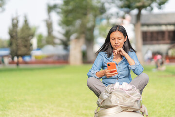 Bored ethnic woman scrolling smartphone in park